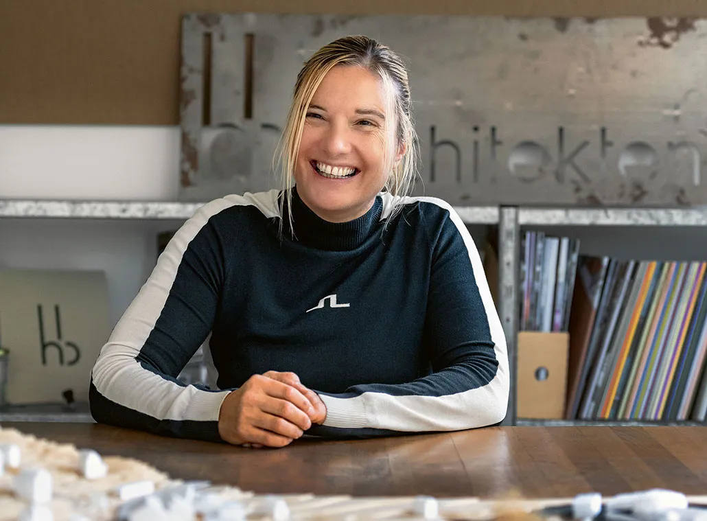 Ursula Schwaller sitzt lachend am Tisch vor einem Architekturmodell