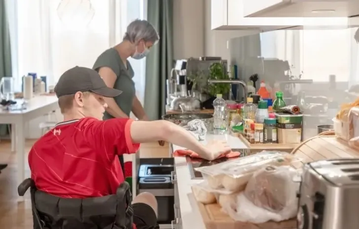 Junger Rollstuhlfahrer beim Kochen