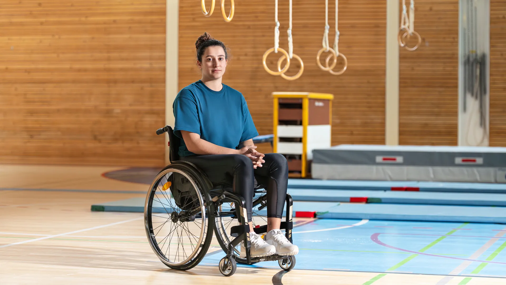 Giulia Damiano est assise dans son fauteuil roulant dans une salle de gymnastique.