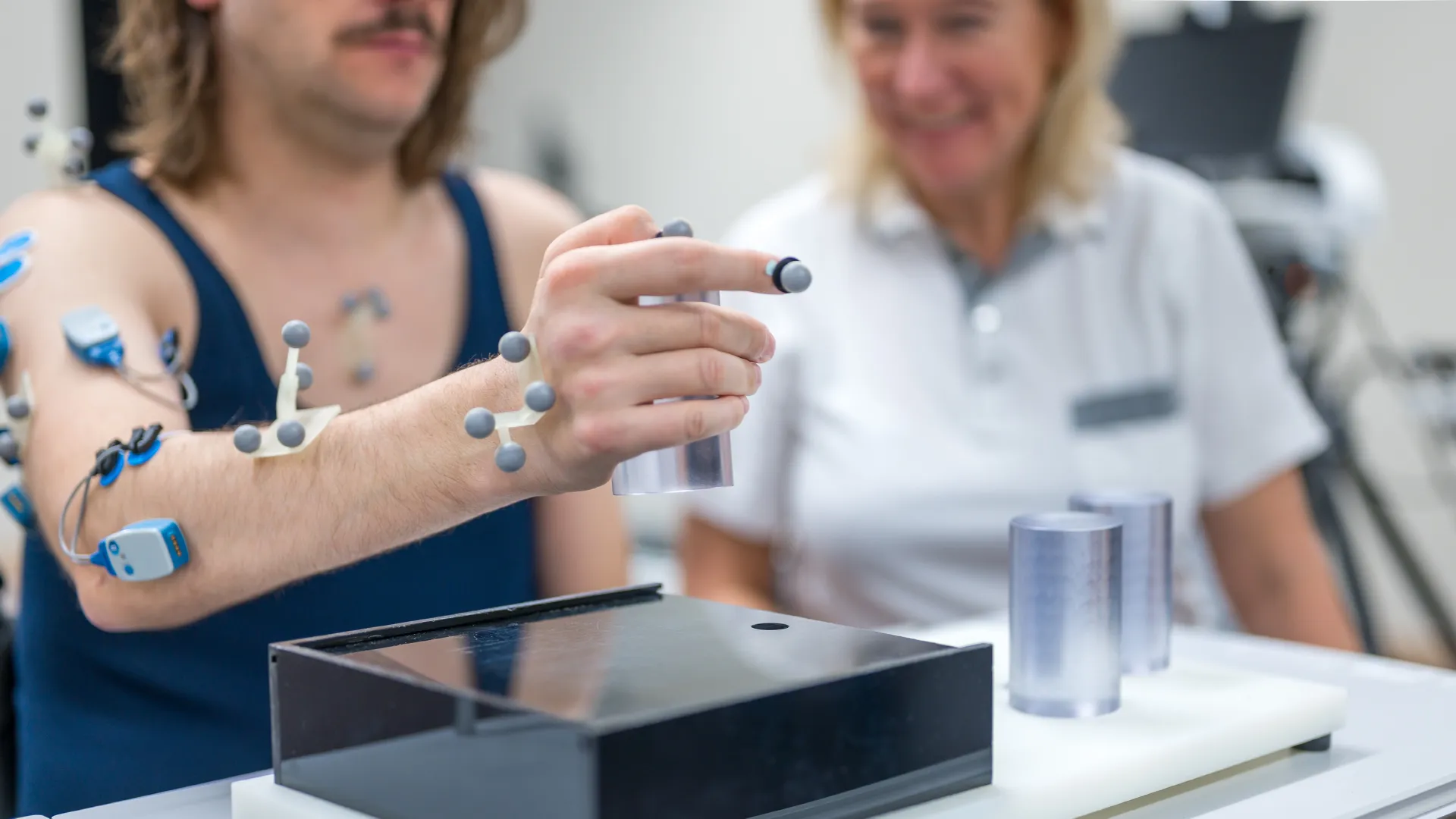 Unter anderem wird das Greifen und Anheben eines Zylinders mit dem Patienten getestet. Im Alltag könnte es sich dabei um einen Trinkbecher handeln.