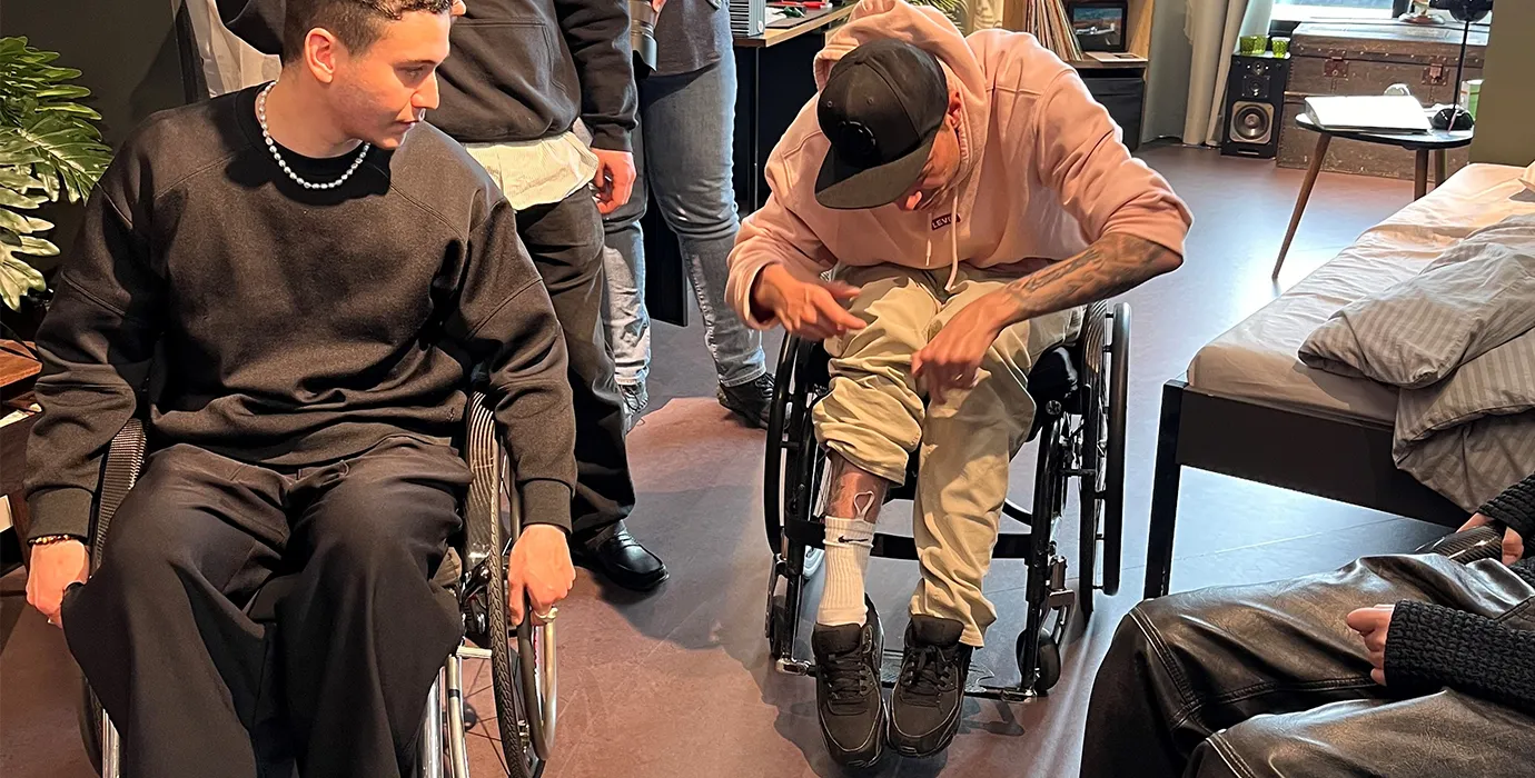 Tetraplegiker Florian Bickel zeigt den Besuchenden aus Genf, dass er dank Schlaufen an seinen Socken diese gut selber anziehen kann. 