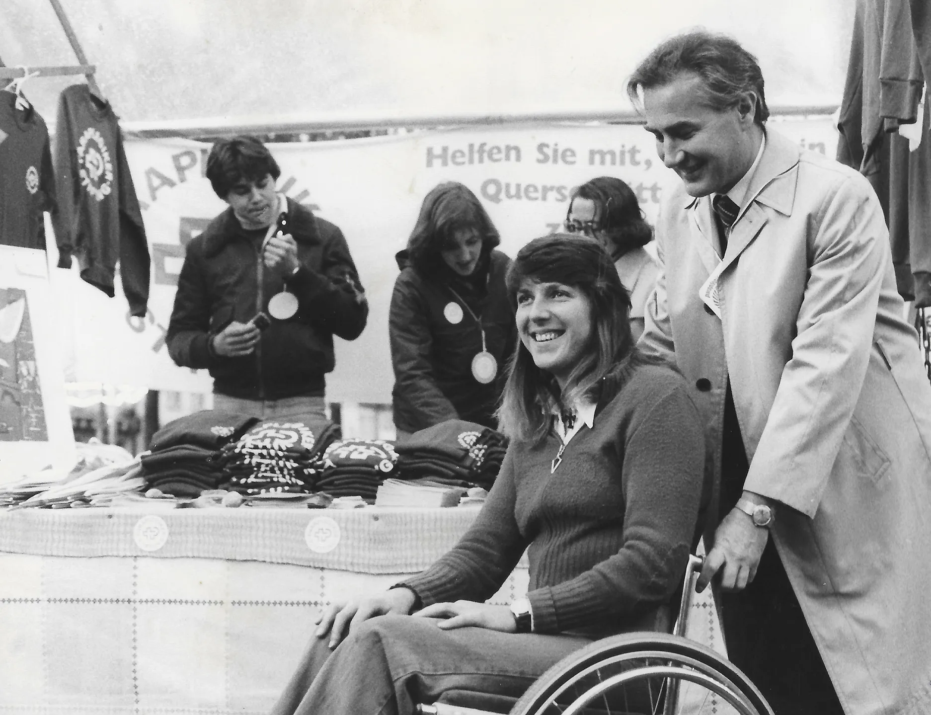 Rosa Zaugg auf einem Schwarz-Weiss-Foto vor einem Werbe-Stand der Schweizer Paraplegiker-Stiftung.