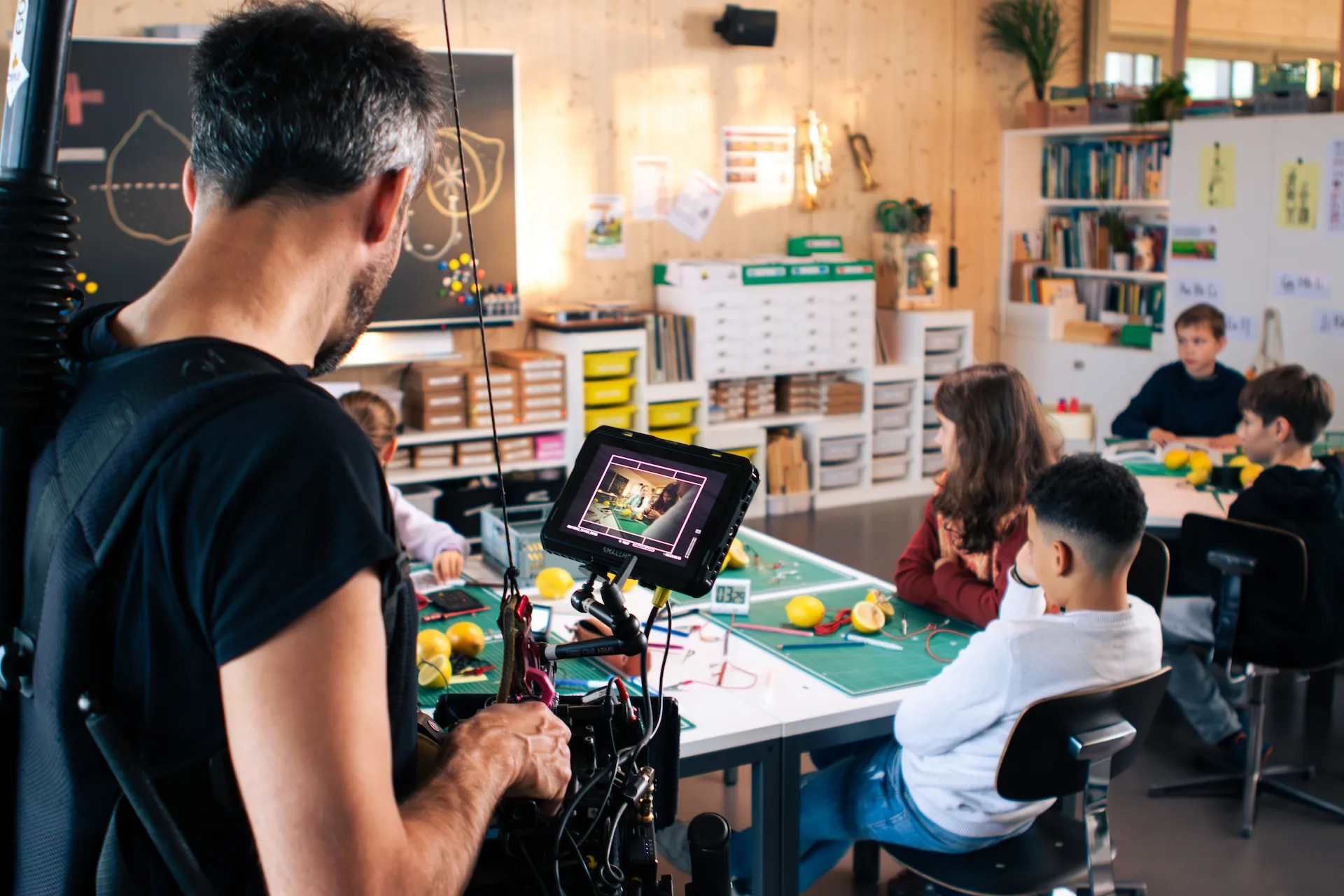 Regisseur Lukas Wälli filmt in einem Schulzimmer mehrere Kinder, die an Pulten sitzen und ein Zitronen-Experiment durchführen.