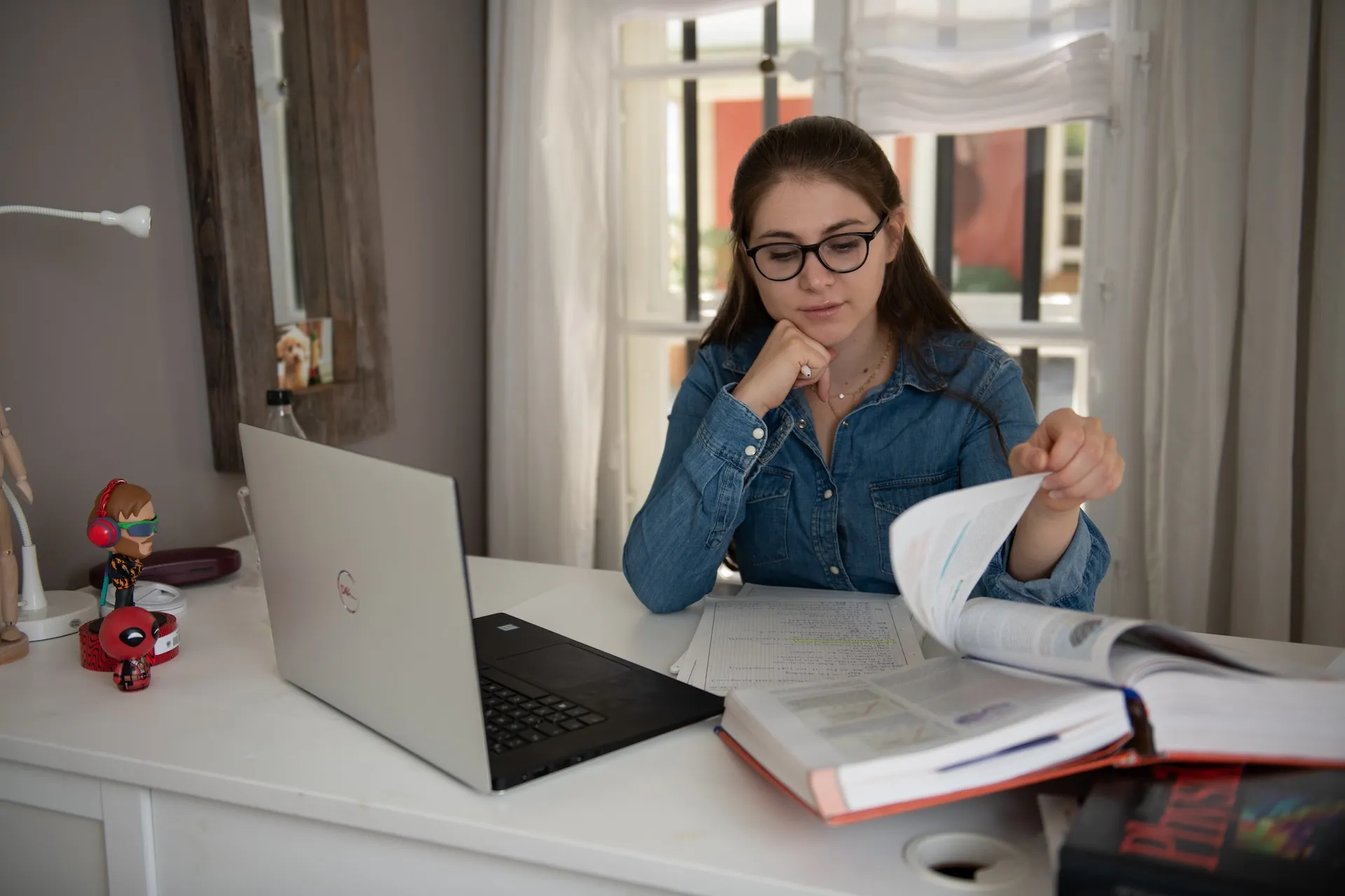 Chiara sitzt am Pult vor ihrem Laptop und einem dicken Buch beim Lernen.