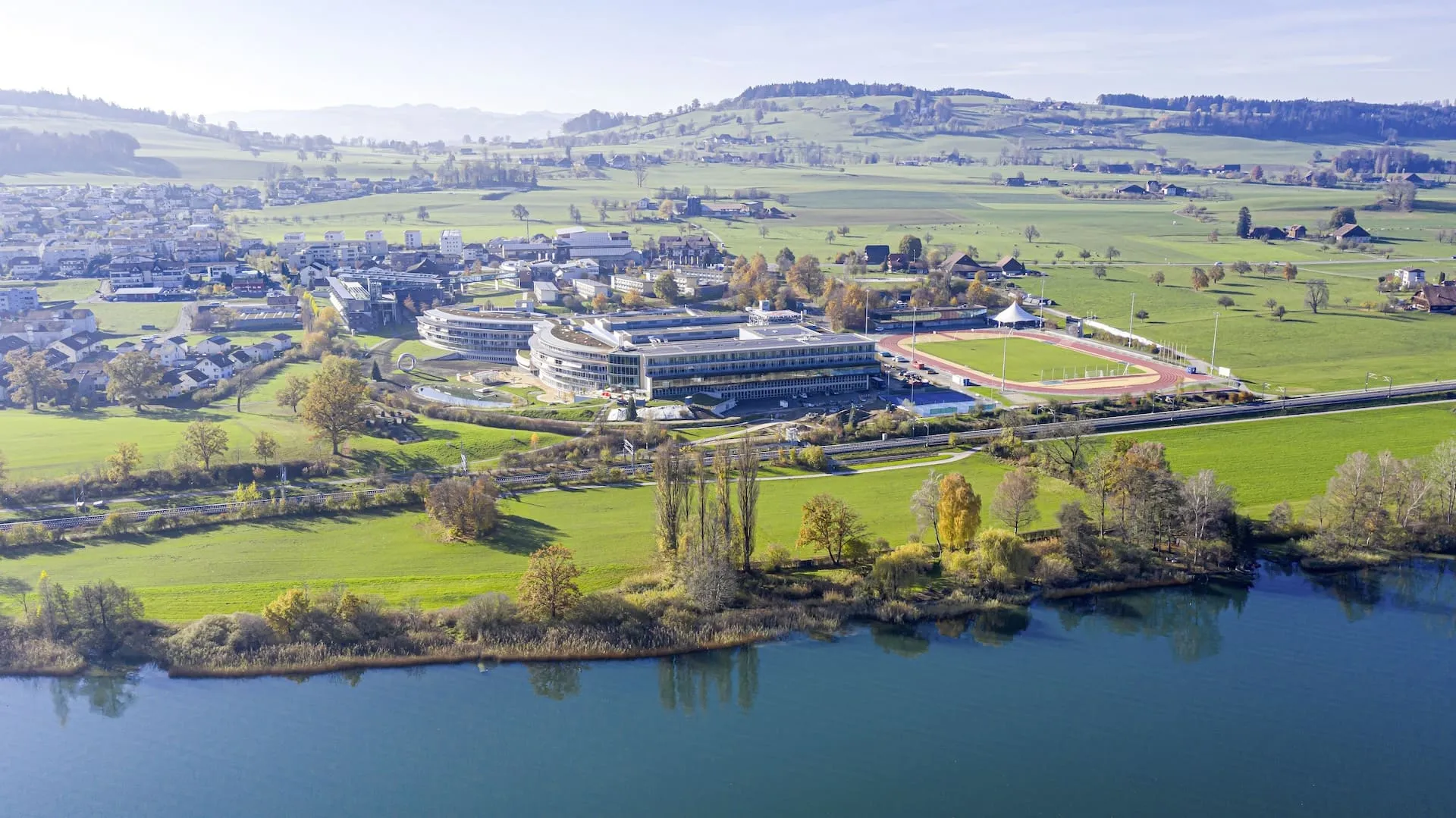 Der Campus Nottwil aus der Vogelperspektive im Jahr 2021. Im Vordergrund sieht man den See und das Blickfeld reicht bis zum Horizont.