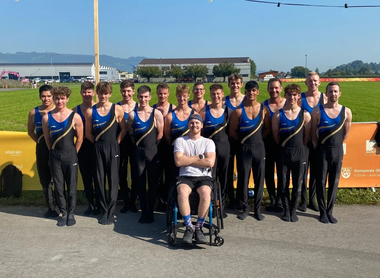 Tim sitzt im Rollstuhl vor seinen in Reih und Glied aufgestellten Kollegen vom Turnverein Neftenbach - draussen auf einem Sportplatz.