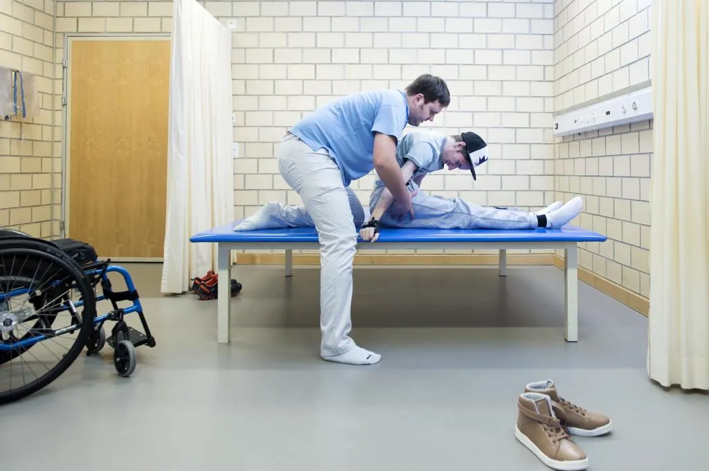 Nach dem anstrengenden Transfer vom Rollstuhl auf die Liege beginnt die Physiotherapie.